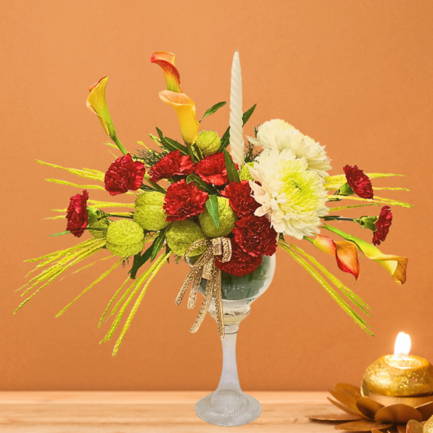 name and description -glass vase floral arrangement with green balloon flowers calla lilies white disbuds red carnations and white candle best floral arrangement for festive Diwali celebrations
